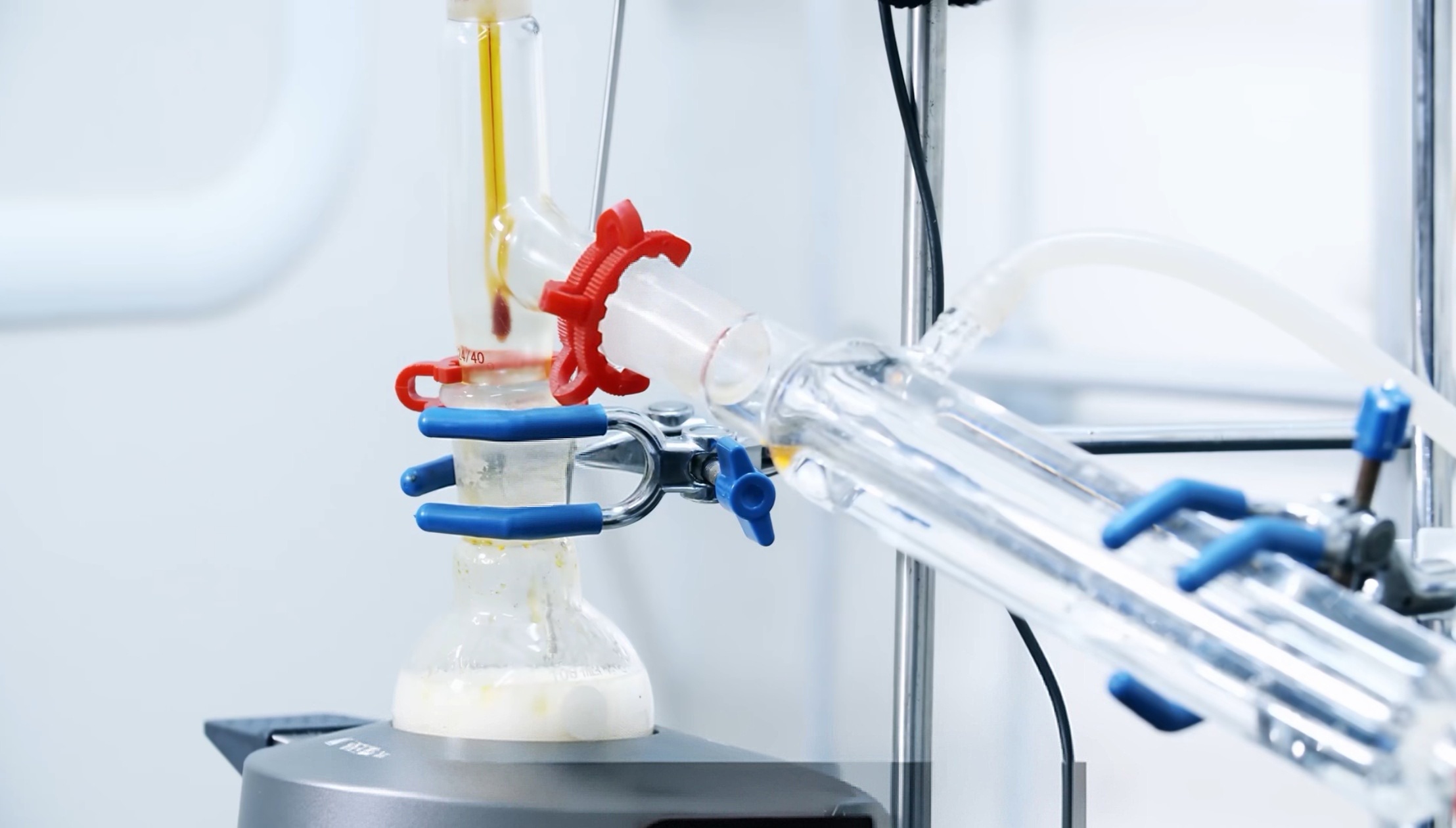 Close-up of a distillation head and condenser assembly showing joints, clips, thermometer position, and support hardware in an organic lab setup