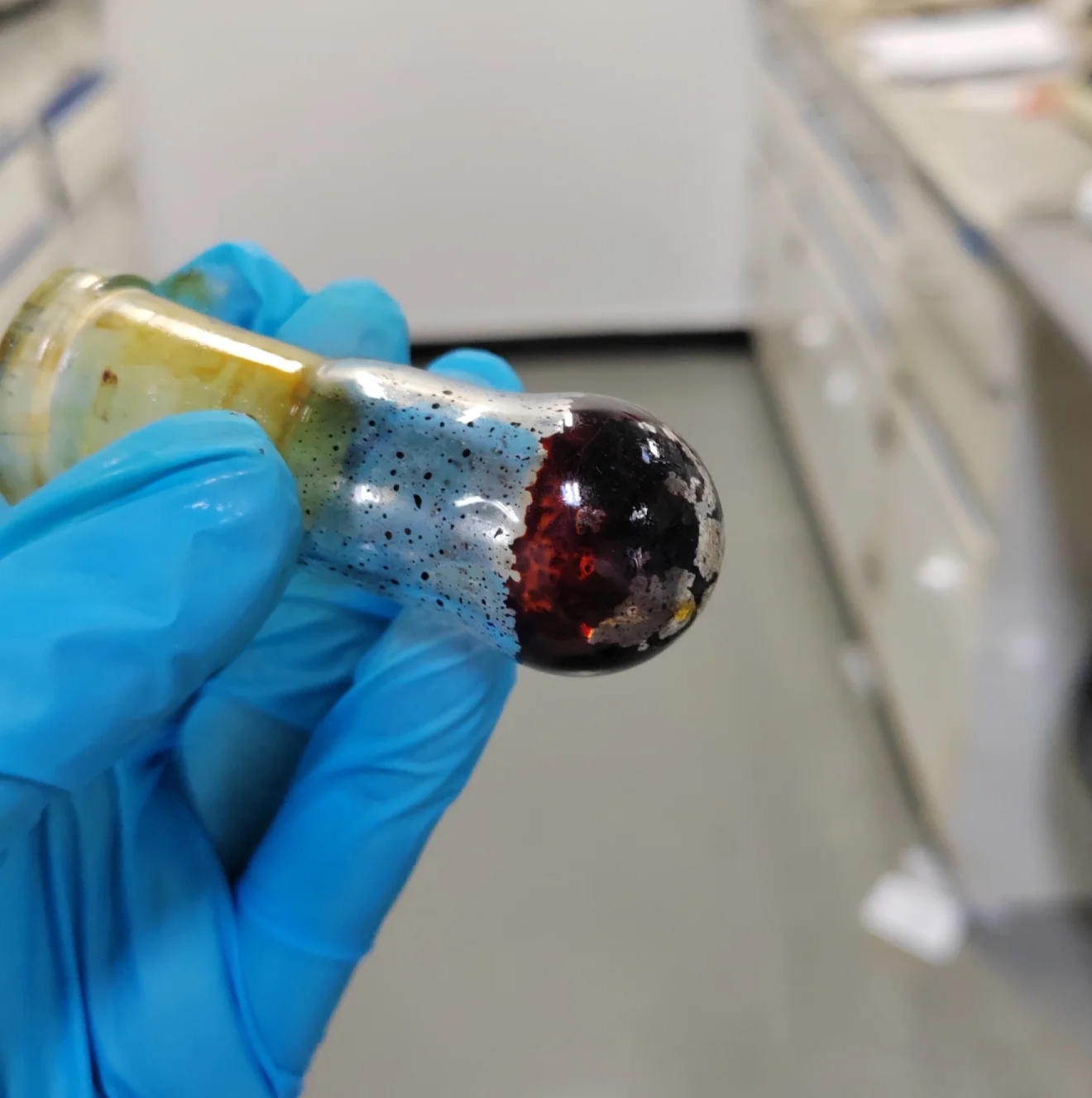 Concentrated organic reaction residue in a round-bottom flask showing dark red thermal decomposition signs.