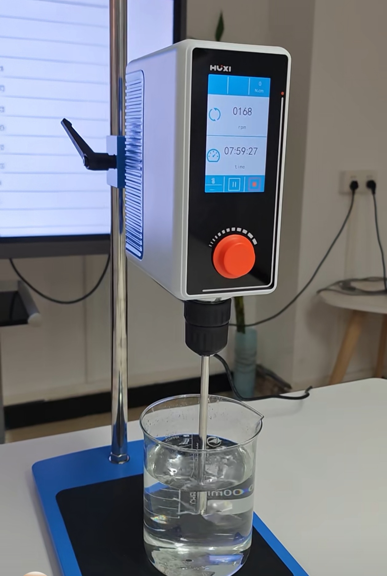 Overhead stirring setup with a top-mounted motor, stirrer shaft, and impeller mixing a reaction vessel.